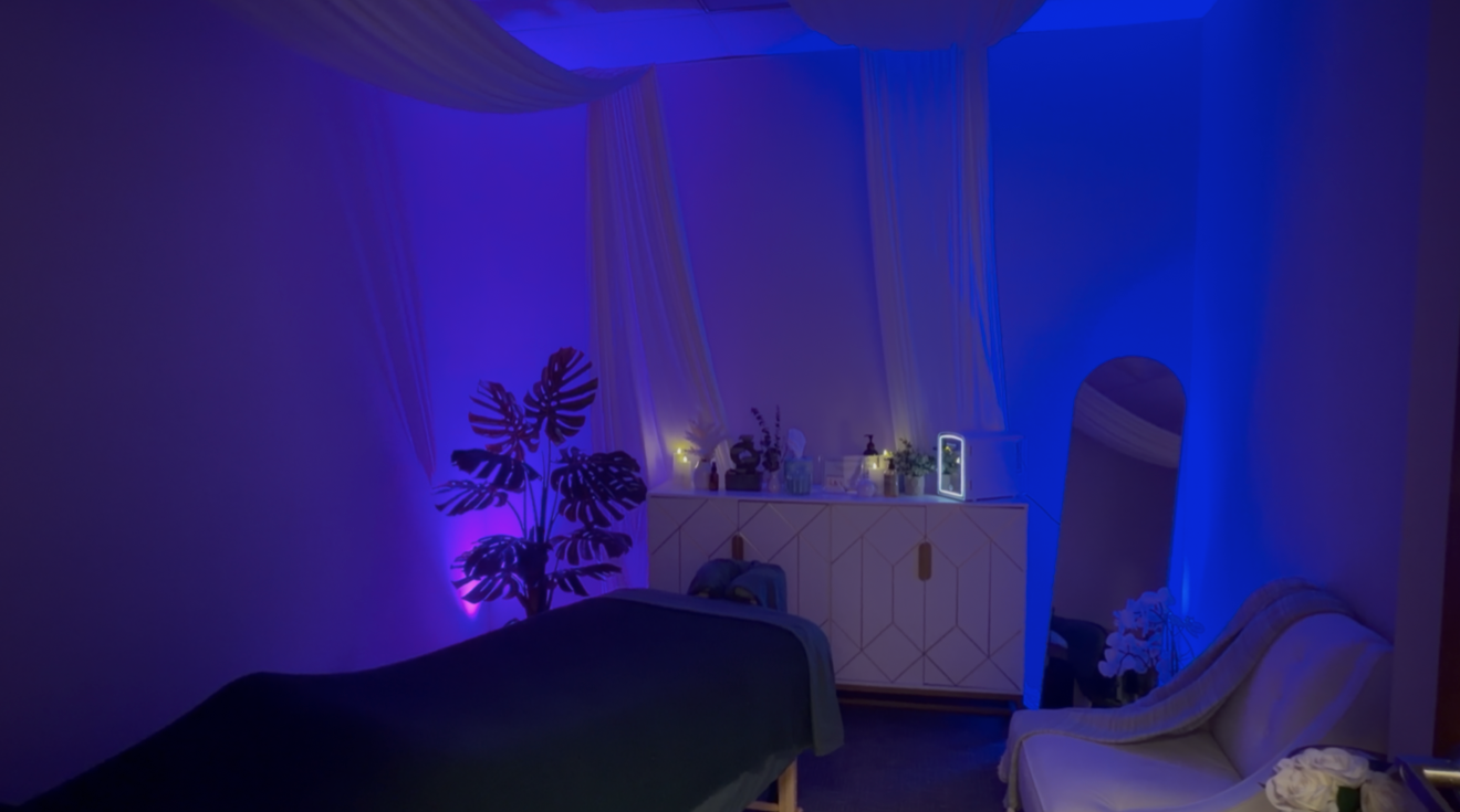 Organic Awakenings massage studio with massage table, soft blue and purple lighting, draped canopy and seating